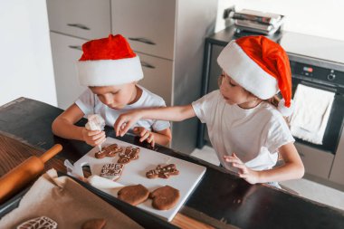 Yeni yıl beklentisi. Küçük çocuk ve kız mutfakta Noel kurabiyeleri hazırlıyorlar..