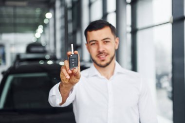 Anahtarları var. Beyaz gömlekli genç adam modern otomobille içeride..