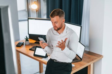 Yoğun bir gün. Resmi giyinmiş genç işadamı birden fazla ekranla ofiste..