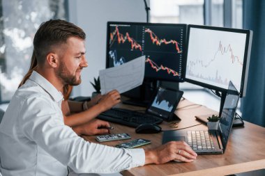 Bir kadınla. Resmi giyinmiş genç işadamı birden fazla ekranla ofiste..