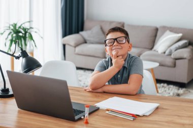 Küçük çocuk evde dizüstü bilgisayar kullanarak online dersler alıyor..