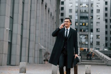 Resmi kıyafetlerle. Siyah takım elbiseli ve kravatlı iş adamı şehir dışında..