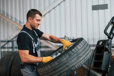 Kırık tekerlek. Üniformalı adam otomobil servisinde çalışıyor..