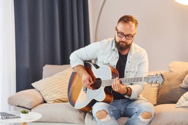 Sıcak bir atmosfer. Gündelik giysiler içinde ve akustik gitarlı bir adam içeride..