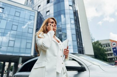 Telefonda sohbet ediyorduk. Resmi kıyafetli kadın gündüz vakti açık havada dikiliyor..