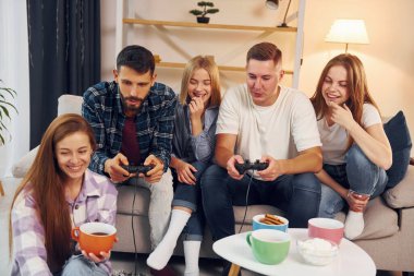 Oyun oynamak için joystickleri kullanmak. Bir grup arkadaş içeride parti veriyor..