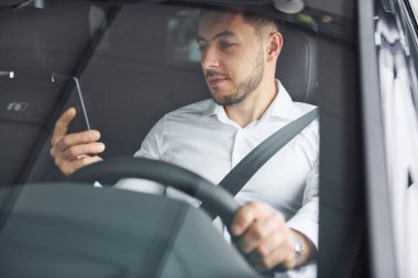 Başarılı bir adam. Beyaz gömlekli genç adam modern bir otomobilin içinde oturuyor..