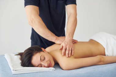 Genç bir kadın masaj yaparken sırt üstü uzanıyor..