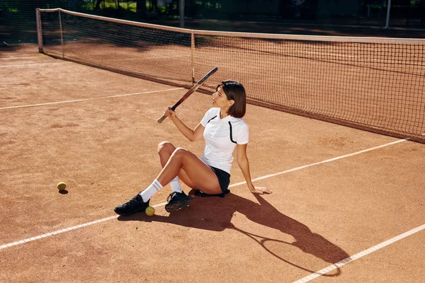 地面に座って 女子テニス選手は昼間はコートにいる — ストック写真