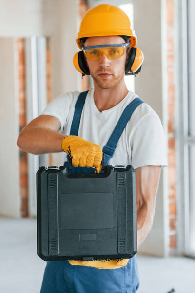 Modern repair. Young man working in uniform at construction at daytime.