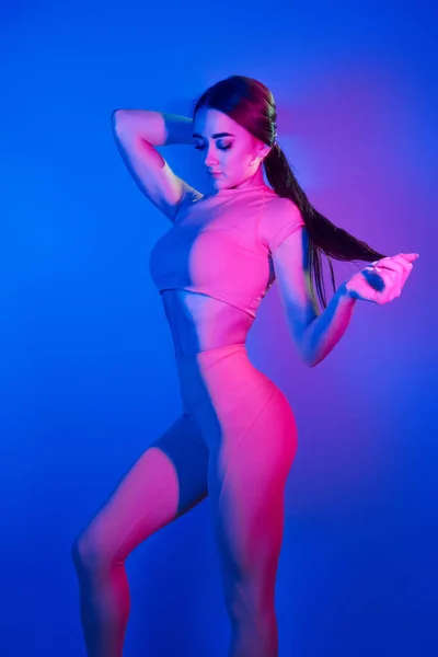 Pokazuje Ciało Modna Młoda Kobieta Stojąca Studio Neonowym Światłem — Zdjęcie stockowe