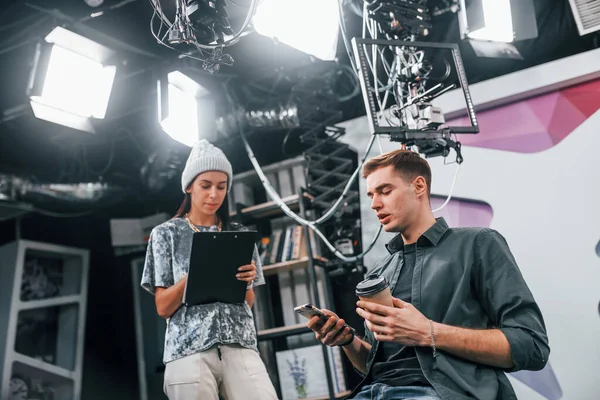 Young man is preparing for TV online broadcast. Woman helps with make up.