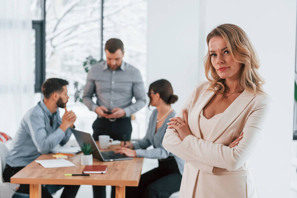 Женщина в белой одежде стоит перед своими сотрудниками. Группа бизнесменов, работающих над проектом в офисе.