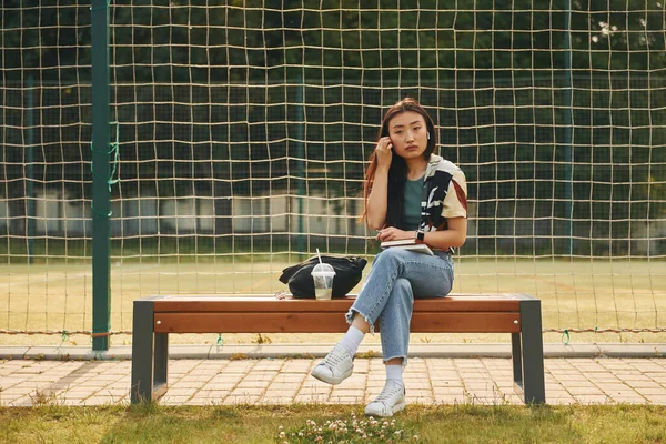 Sitzt Gegen Den Sportplatz Junge Asiatische Frau Ist Tagsüber Draußen — Stockfoto