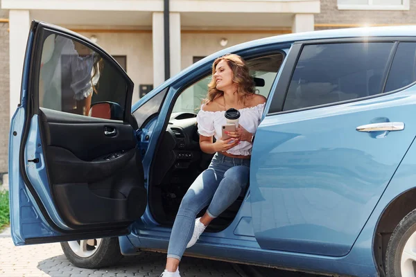 Young woman in casual clothes with her electromobile outdoors at daytime.