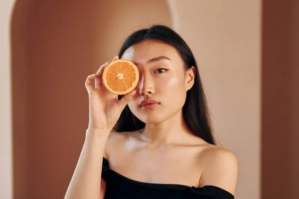 Куском Апельсина Молодая Серьезная Азиатка Стоит Помещении — стоковое фото