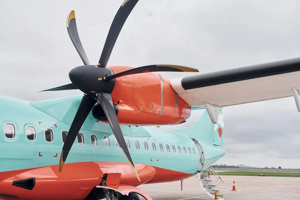 Retro style. Turboprop aircraft parked on the runway at daytime.