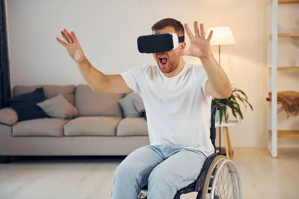 In VR glasses. Disabled man in wheelchair is at home.