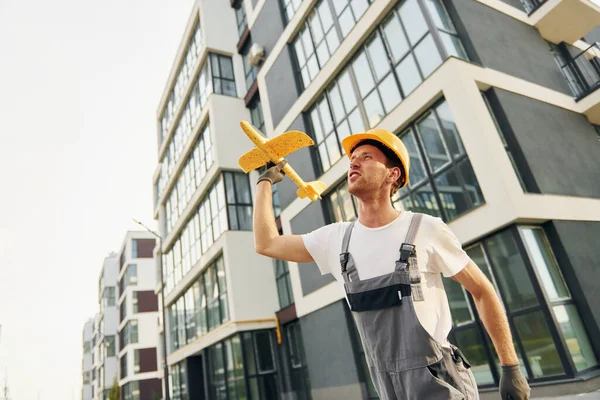 Modern şehir. Gündüz vakti inşaatta üniformalı genç bir adam çalışıyor..