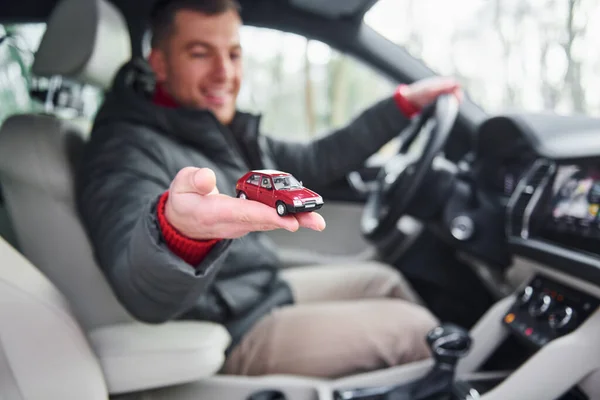 Mann Sitzt Auto Und Hält Kleines Rotes Spielzeugauto Der Hand — Stockfoto