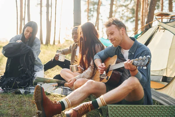 Hombre Toca Guitarra Grupo Jóvenes Viaja Juntos Bosque Durante Día — Foto de Stock