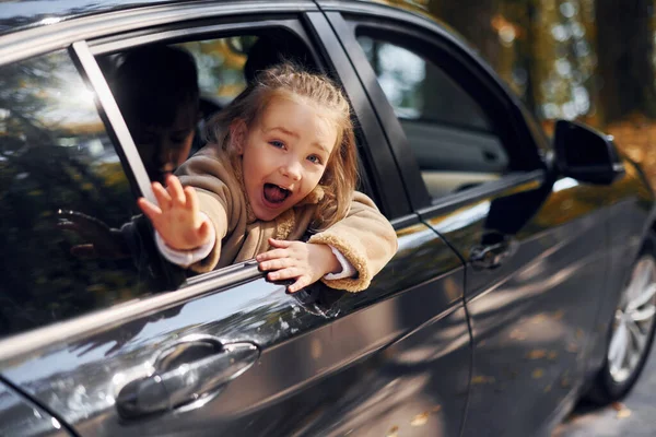 黒い車の中に座って窓を見ている少女 ロイヤリティフリーのストック画像