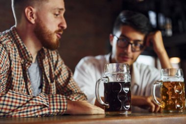 İnsanlar sıradan kıyafetlerle barda oturup sohbet ediyorlar..