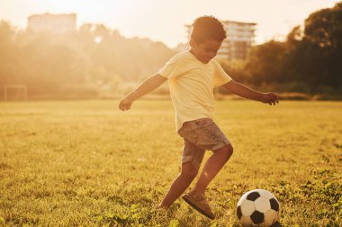 Futbol oynuyor. Afrikalı Amerikalı çocuk yaz günlerinde tarlada eğleniyor..