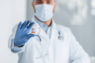 COVID-19 aşısıyla test tüpünü tutuyorum. Klinikte beyaz önlüklü profesyonel doktor var..