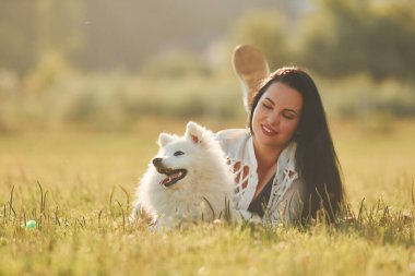 Yere yatıyorlardı. Köpeğiyle bir kadın güneşli bir günde sahada eğleniyor..
