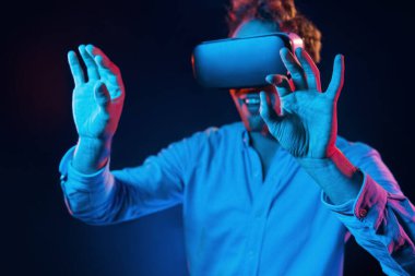 Sanal gözlük oyun deneyimi. Neon ışıkları. Genç Avrupalı adam karanlık stüdyoda..