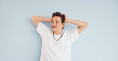 Genç eşcinsel adam stüdyoda duruyor ve kameraya poz veriyor..