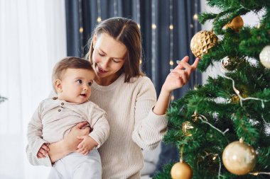 Noel ağacı süslüyorum. Anne ve küçük kızı evde birlikte..