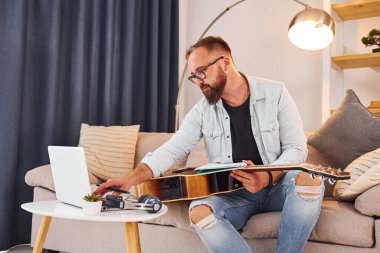 Yaratıcılık kavramı. Gündelik giysiler içinde ve akustik gitarlı bir adam içeride..