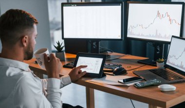 Bilgiye bakıyorum. Resmi giyinmiş genç işadamı birden fazla ekranla ofiste..