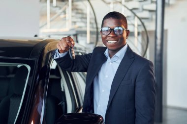 Arabanın yanında duruyor. Siyah takım elbiseli genç Afro-Amerikan iş adamı Ototalon..