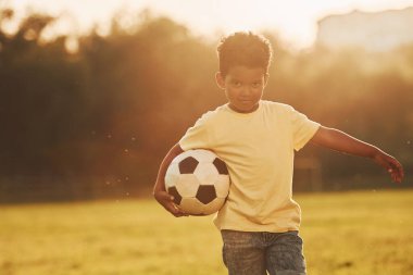 Genç futbolcu. Afrikalı Amerikalı çocuk yaz günlerinde tarlada eğleniyor..