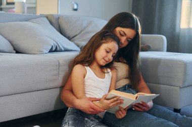 Beyaz tenli genç bir anne kızıyla birlikte evde..