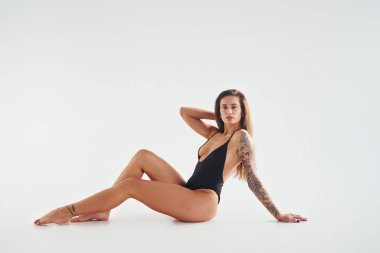 Yerde oturuyordu. Stüdyoda seksi vücutlu, baştan çıkarıcı, güzel bir kadın poz veriyor..