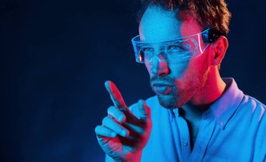 Neon ışıkları. Genç Avrupalı adam karanlık stüdyoda..