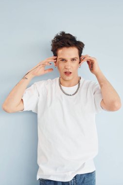 Genç eşcinsel adam stüdyoda duruyor ve kameraya poz veriyor. Kırmızı renkli dudaklar..