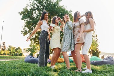 Farklı tarz kıyafetlerle. Bir grup genç yaz günü parkta parti veriyor..