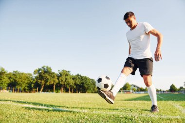 Güneşli bir gün. Genç futbolcu spor sahasında antrenman yapıyor..