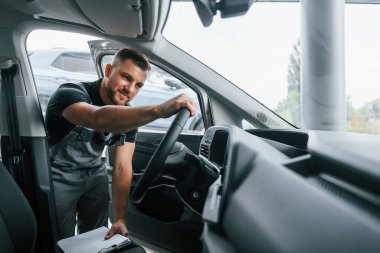 Kalite kontrolü. Üniformalı adam gündüz vakti otosalonda çalışıyor..