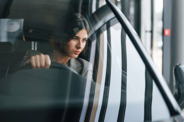 Ön manzara. Yeni arabayı test eden kadın. Modern otomobilde kapalı bir yerde oturuyor..