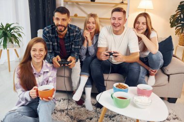 Oyun oynamak için joystickleri kullanmak. Bir grup arkadaş içeride parti veriyor..