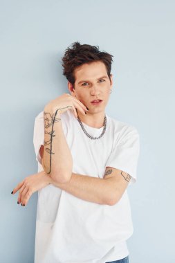 Genç eşcinsel adam stüdyoda duruyor ve kameraya poz veriyor. Kırmızı renkli dudaklar..