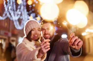 Ellerinde maytaplarla. Mutlu genç çift sokakta yeni yılı kutluyor..