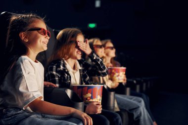 Patlamış mısırla. Bir grup çocuk sinemada oturup birlikte film izliyorlar..