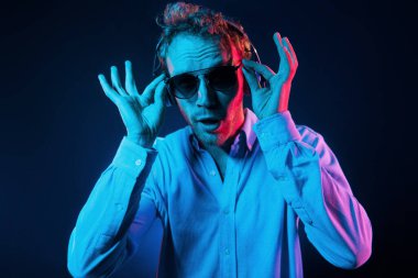 Müziği dinliyor. Neon ışıkları. Genç Avrupalı adam karanlık stüdyoda..